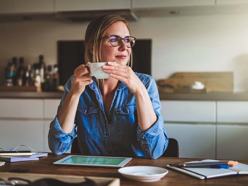 Eine Frau genießt eine Tasse Kaffee, während sie bequem zu Hause sitzt