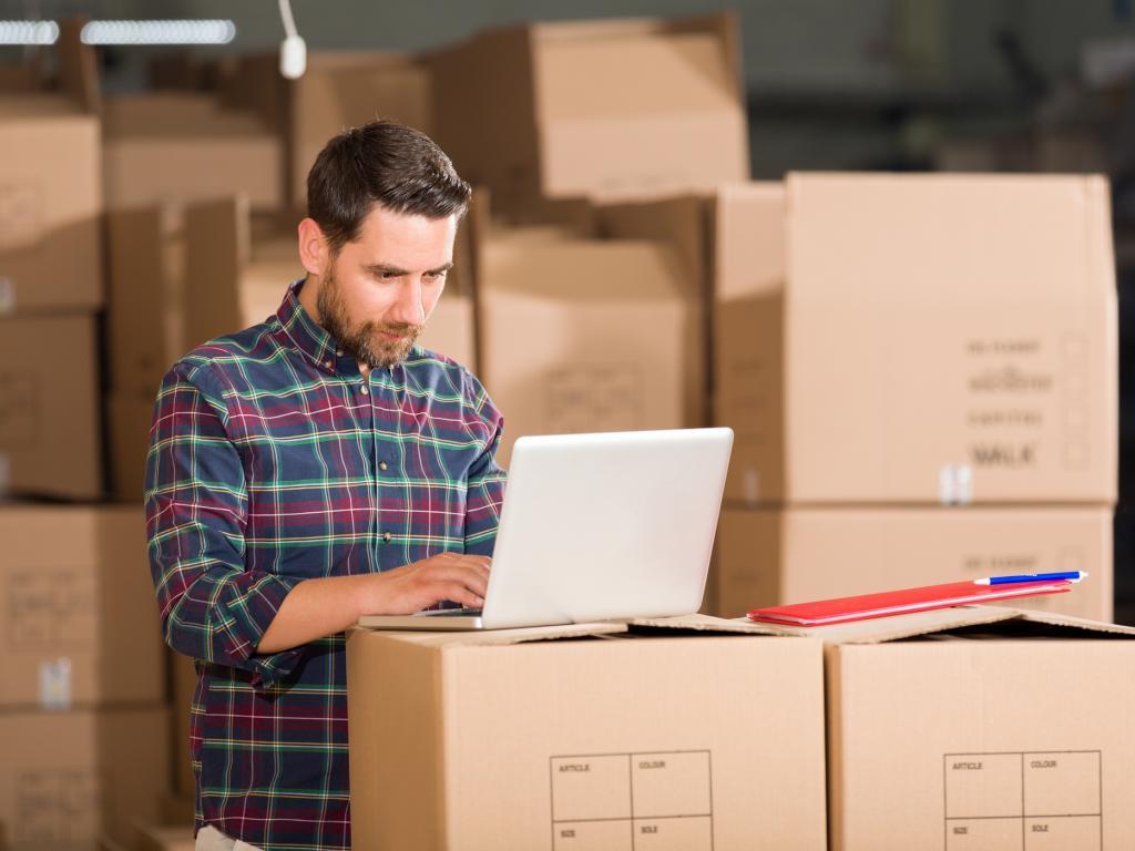 Man with laptop in warehouse L